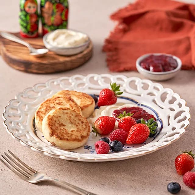Syrniki served with sour cream, berries and cherry jam